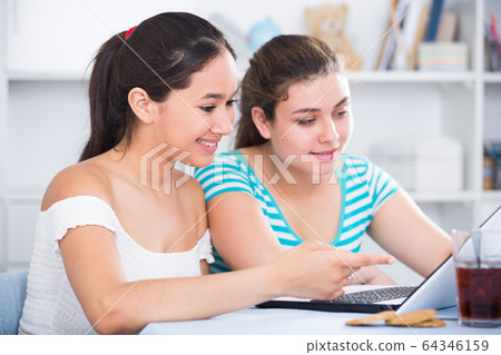 Cheerful teens girls using laptop Cheerful teens girls using laptop 64346159