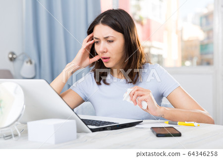 Upset girl student looking tired with laptop at table in home Upset girl student looking tired with laptop at table in home 64346258