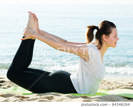 Woman 20-30 years old is practicing stretching in white T-shirt Woman 20-30 years old is practicing stretching in white T-shirt 64346264