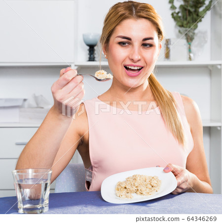 Sporty girl is enjoying breakfast with oatmeal porridge Sporty girl is enjoying breakfast with oatmeal porridge 64346269