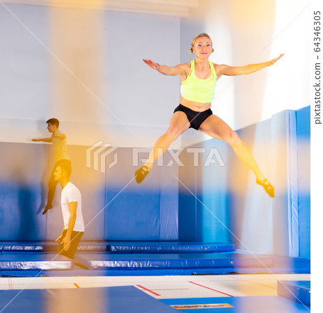 Woman training in trampoline center 64346305