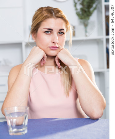 Young female is thoughtful and bored sitting alone Young female is thoughtful and bored sitting alone 64346307