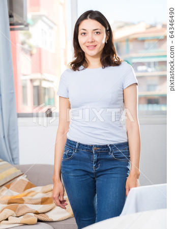 Girl dressed blue jeans standing at room in home interior Girl dressed blue jeans standing at room in home interior 64346490