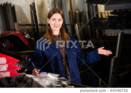 Young female standing with notepad in production workshop 64346730