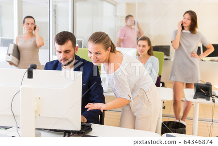 Successful businesswoman helping to man coworker working at computer 64346874