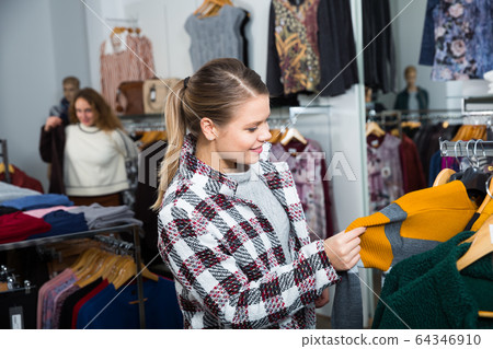 Woman choosing cardigan in clothing shop Woman choosing cardigan in clothing shop 64346910