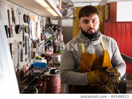 Blacksmith in metalworking workshop 64346913
