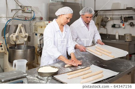 Female baker kneading a dough Female baker kneading a dough 64347156