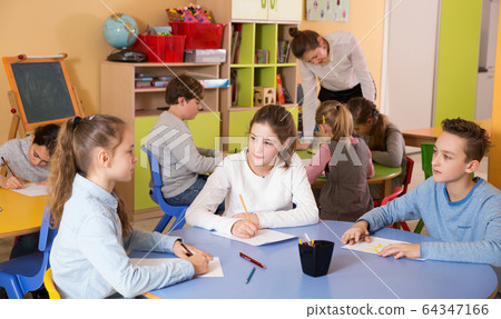 boys and girls sitting and teacher helping drawing boys and girls sitting and teacher helping drawing 64347166