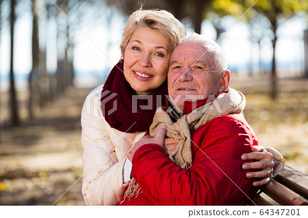 Mature couple sitting in park Mature couple sitting in park 64347201