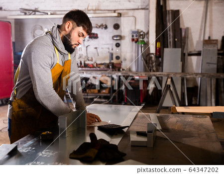 Foreman measures part and takes notes on paper Foreman measures part and takes notes on paper 64347202