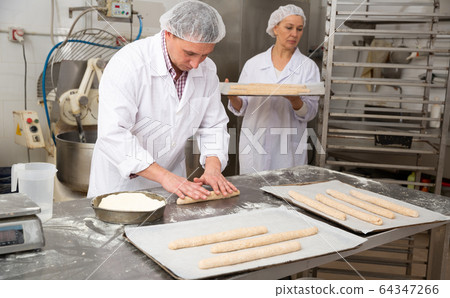 Baker forming baguettes from wholemeal dough Baker forming baguettes from wholemeal dough 64347266