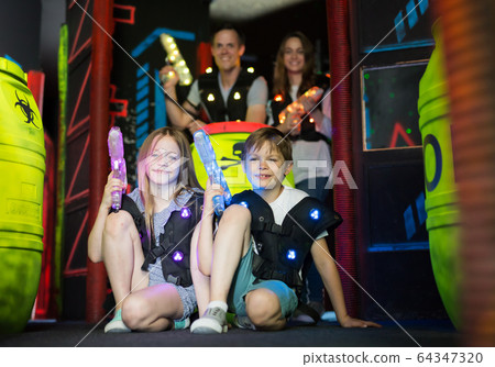 Boy and girl sitting with laser guns 64347320