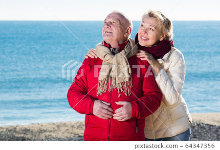 Mature couple pointing on beach Mature couple pointing on beach 64347356