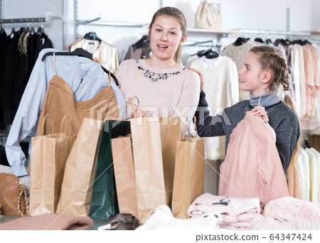 Woman and daughter with purchases in clothing shop Woman and daughter with purchases in clothing shop 64347424