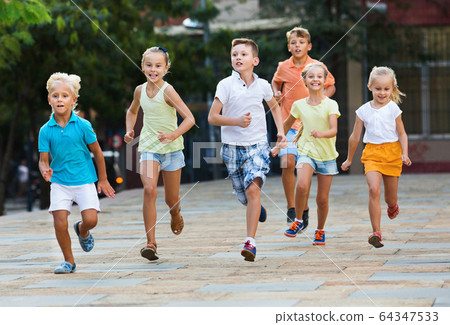 Group of children running outdoors in city street 64347533