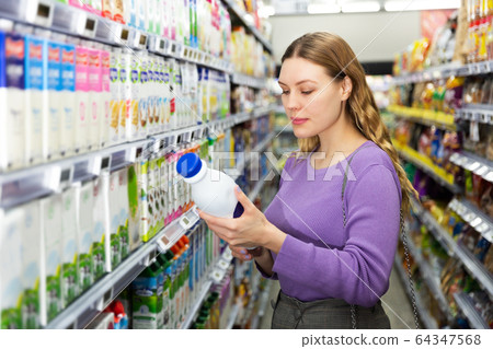 Woman choosing milk in grocery Woman choosing milk in grocery 64347568