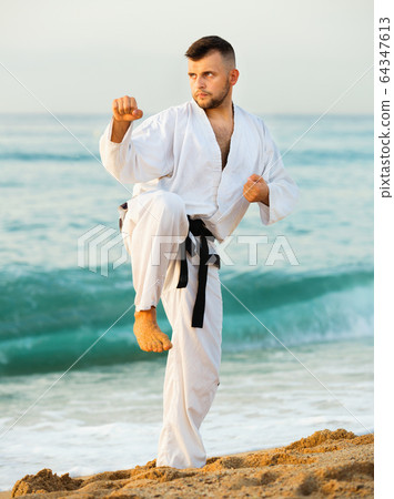 Guy doing karate poses at sunset sea shore Guy doing karate poses at sunset sea shore 64347613