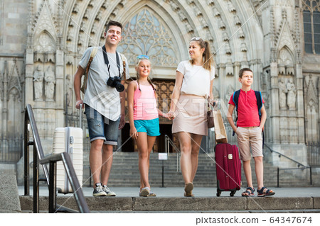 Happy family walking together on city with baggage Happy family walking together on city with baggage 64347674