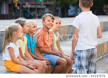 Smiling kids playing charades outdoors Smiling kids playing charades outdoors 64347676