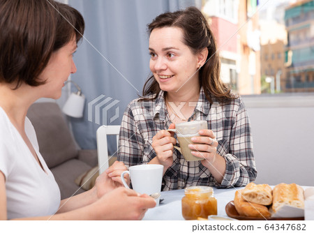 Two woman friends talking and drinking tea in the kitchen 64347682