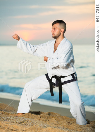 Brunette man doing karate at ocean quay 64347818