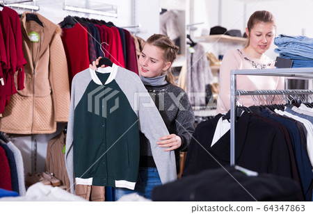 Happy teen girl looking for clothing with mum 64347863