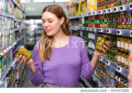Woman is holding jar of preserved olives 64347886
