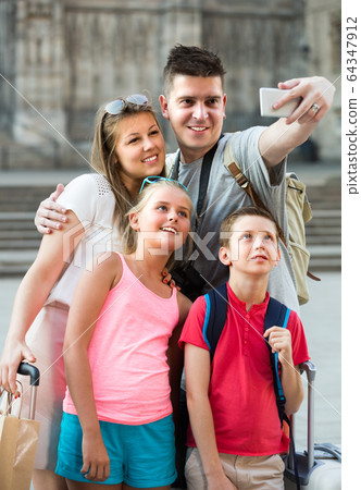 Parents and two children are traveling together, taking selfie 64347912