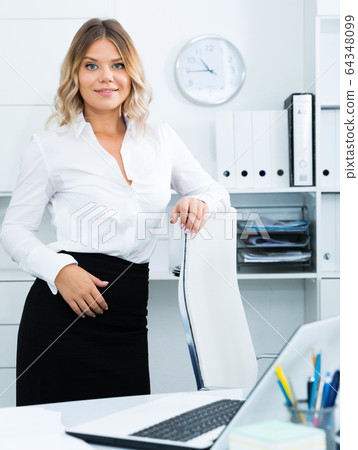 Young girl in business clothes is standing near table in office 64348099