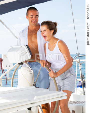 Man and woman steering pleasure yacht 64348140
