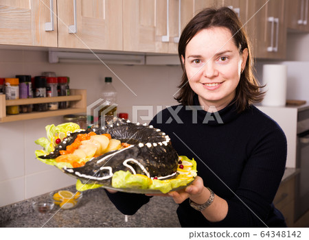 Young woman with dish of fried sturgeon 64348142