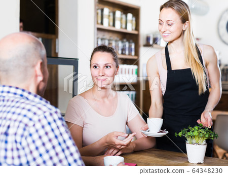 Middle aged man and young woman talking in cozy cafe Middle aged man and young woman talking in cozy cafe 64348230