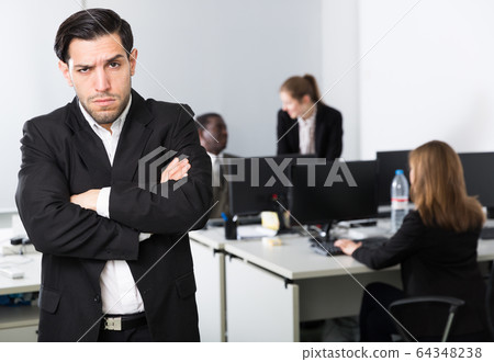 Young businessman standing in office on backround with colleagues Young businessman standing in office on backround with colleagues 64348238