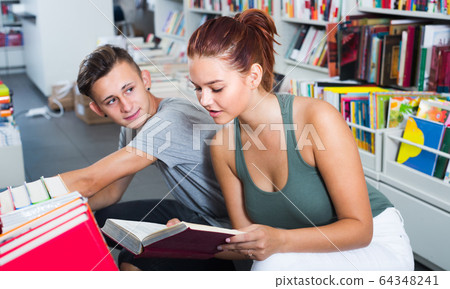 girl and boy teenagers in book store. girl and boy teenagers in book store. 64348241