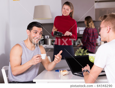 Man helping guy to plan tourist itinerary at hostel kitchen Man helping guy to plan tourist itinerary at hostel kitchen 64348290