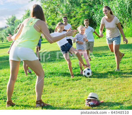 People with kids together outdoors playing football People with kids together outdoors playing football 64348510