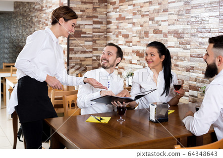 Waitress taking order at table of people 64348643