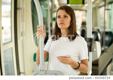 Female using mobile phone in tram Female using mobile phone in tram 64348724