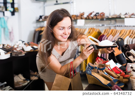 cheerful female customer selecting shoes in footgear center cheerful female customer selecting shoes in footgear center 64348732
