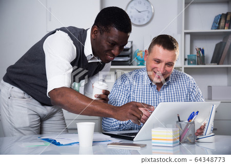 Two businessmen working in the office at the laptop 64348773