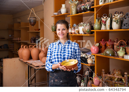 Positive female artisan having ceramics in workshop 64348794