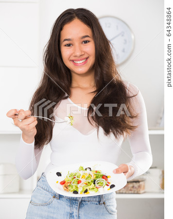 Positive female eating useful salad Positive female eating useful salad 64348864