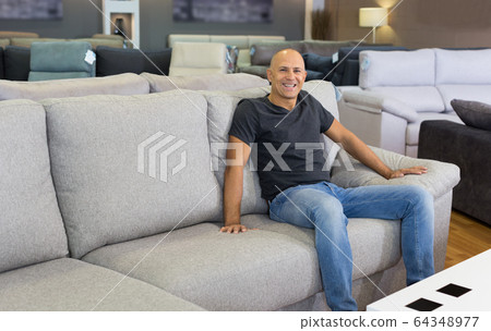 Man sitting and testing new sofa 64348977