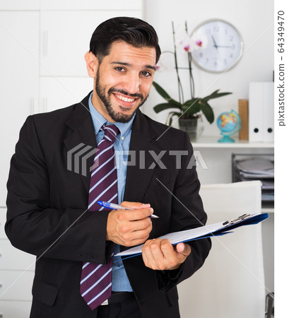Smiling man is signing agreement papers Smiling man is signing agreement papers 64349470