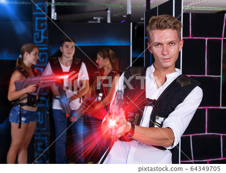 Positive young man with laser pistol and playing laser tag with 64349705