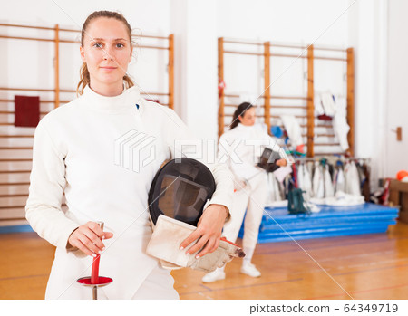 Smiling young female in uniform standing at fencing room Smiling young female in uniform standing at fencing room 64349719