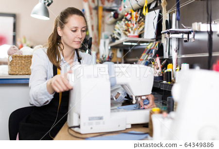 Female tailor working with sewing machine at workshop 64349886