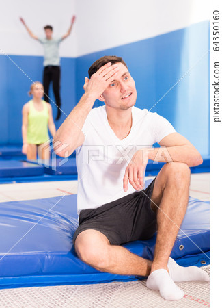 Tired man relaxing after trampoline workout Tired man relaxing after trampoline workout 64350160