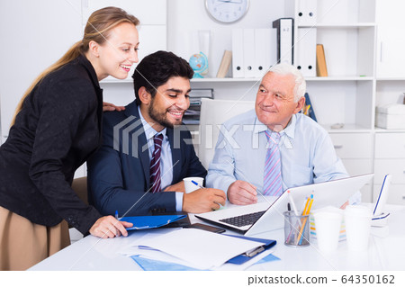 Colleagues are working together at computer 64350162